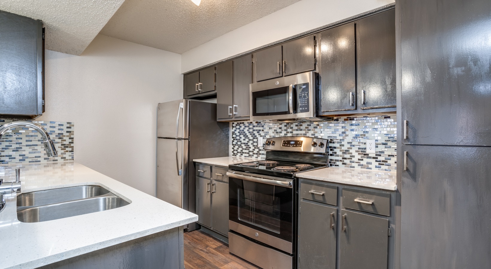 a kitchen with stainless steel appliances and gray cabinets at The Hudson