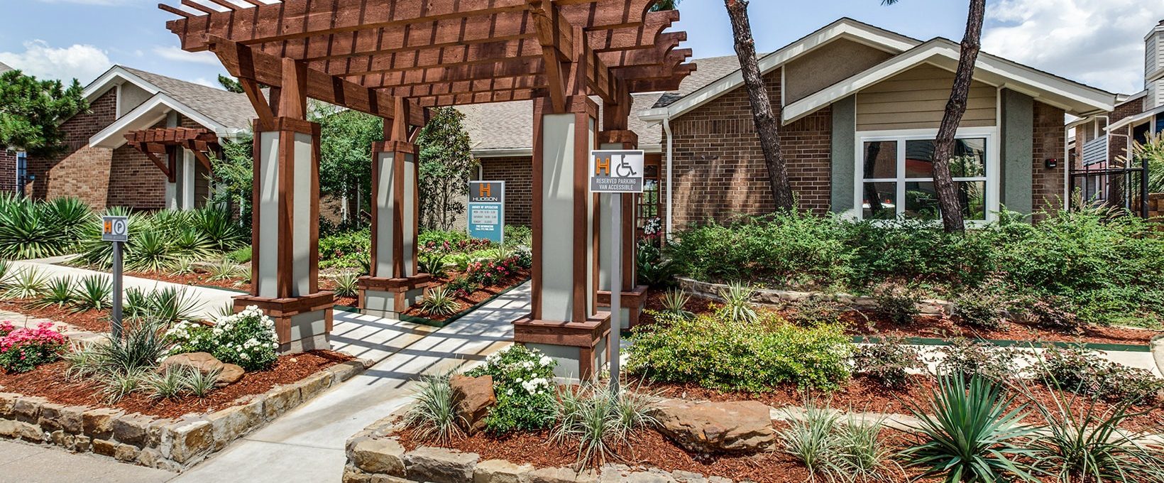 the front entrance to a home with landscaping and a pergol at The Hudson